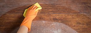 Cleaning soiled parquet in gloves with yellow rag